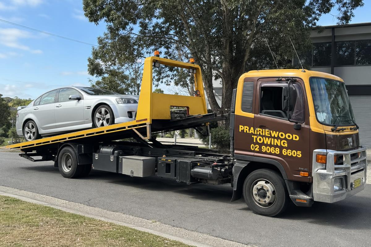 Prairiewood Towing tilt tray truck loading a sedan for car towing